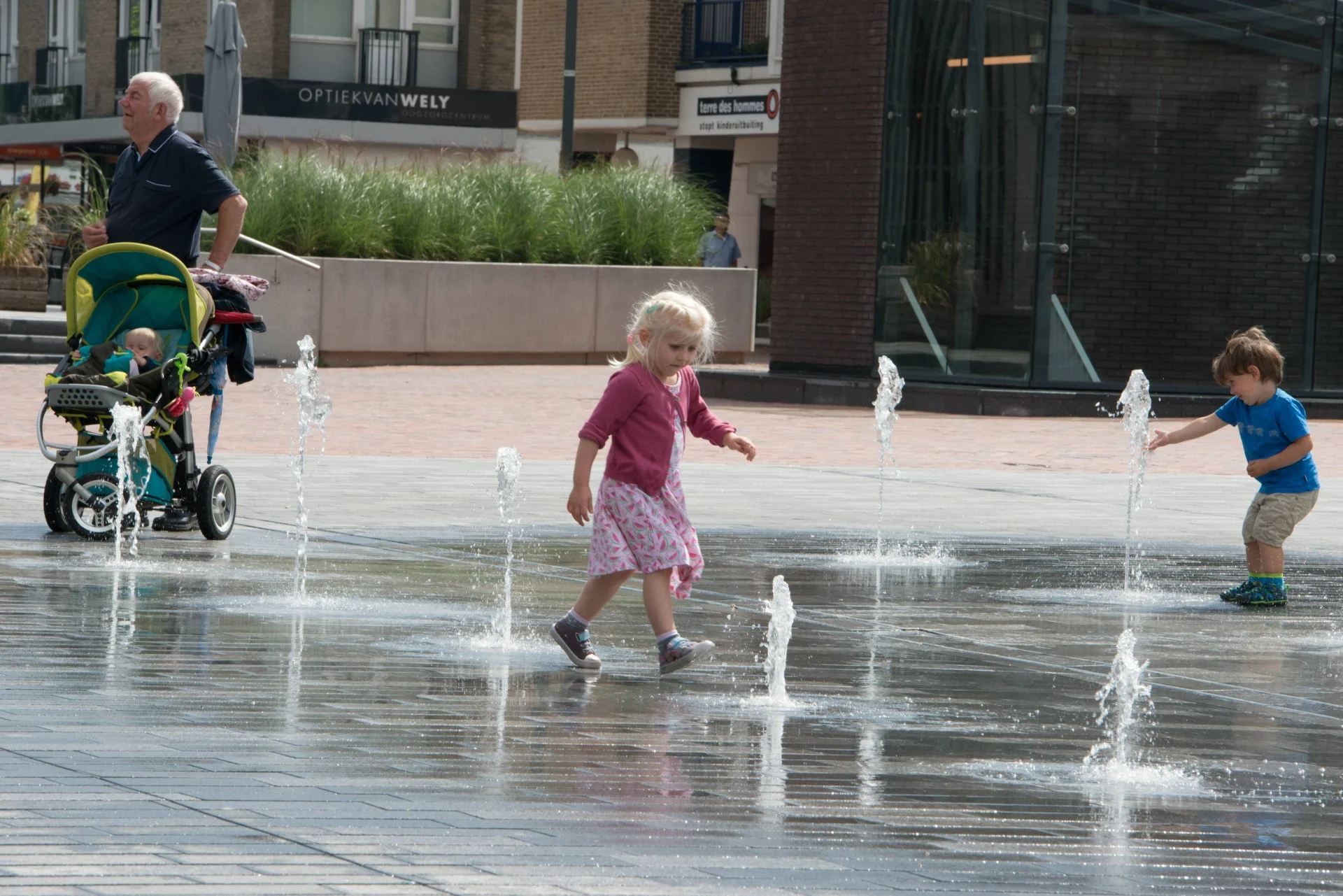 fontein fonteinen aanleg realisatie aannemer maken bouwen plein gemeente stad aannemerij leverancier waterkunstwerken fonteintechniek natuursteen (32) Kinderen en een kinderwagen bij de fonteinen op de Nieuwe Markt in Roosendaal