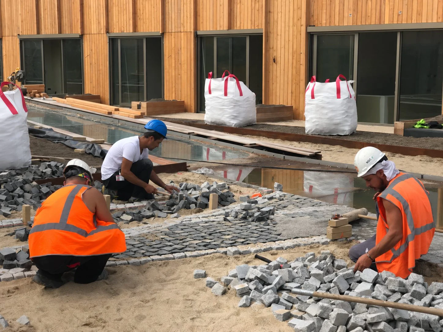 fontein fonteinen aanleg realisatie aannemer maken bouwen plein gemeente stad aannemerij leverancier waterkunstwerken fonteintechniek natuursteen (15) Stratenmakers leggen natuursteen en keitjes voor het waterelement op het dak van Jonas in IJburg