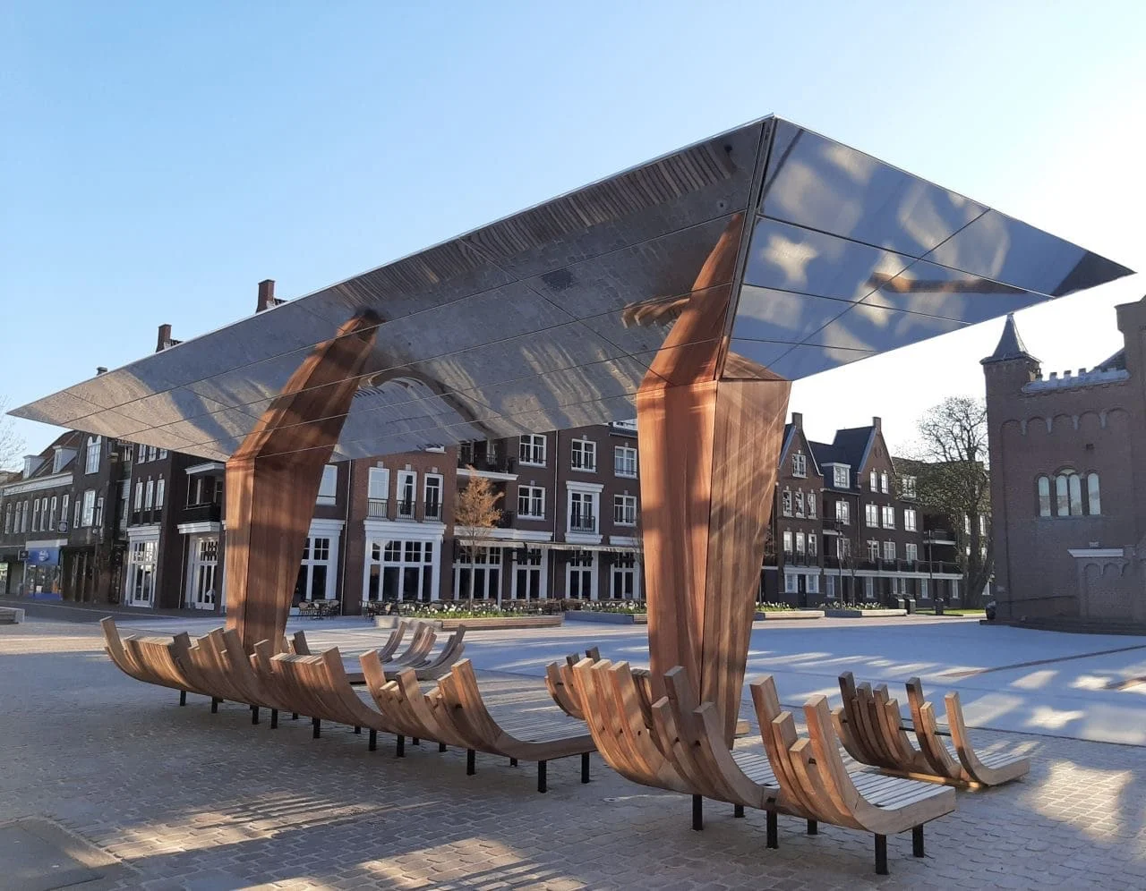 De spiegelkraan met koperkleurige poten en houten banken op het Kerkplein in Hoogeveen