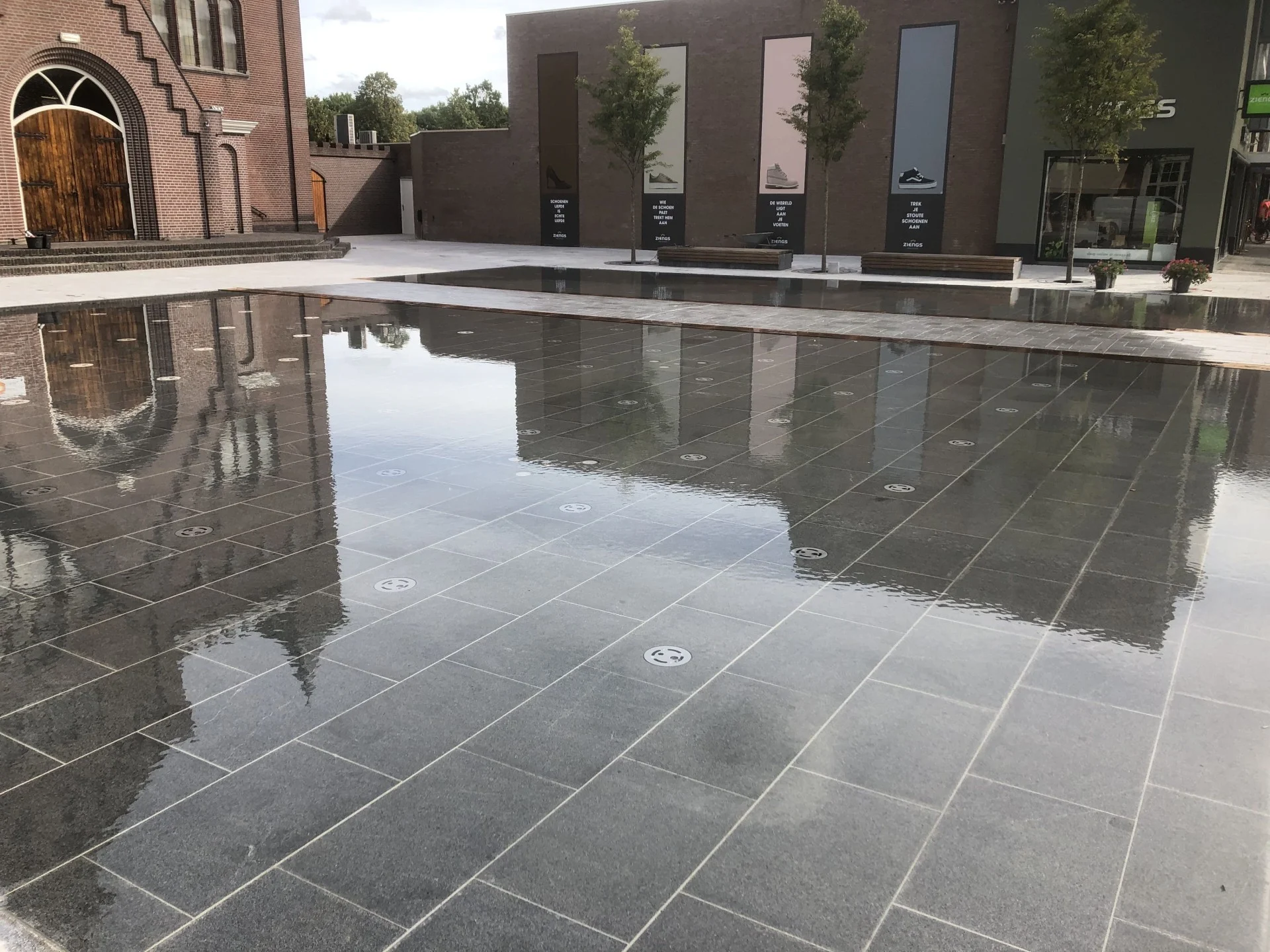 Het spiegelvlak van natuursteen weerspiegelt de kerk op het Kerkplein in Hoogeveen