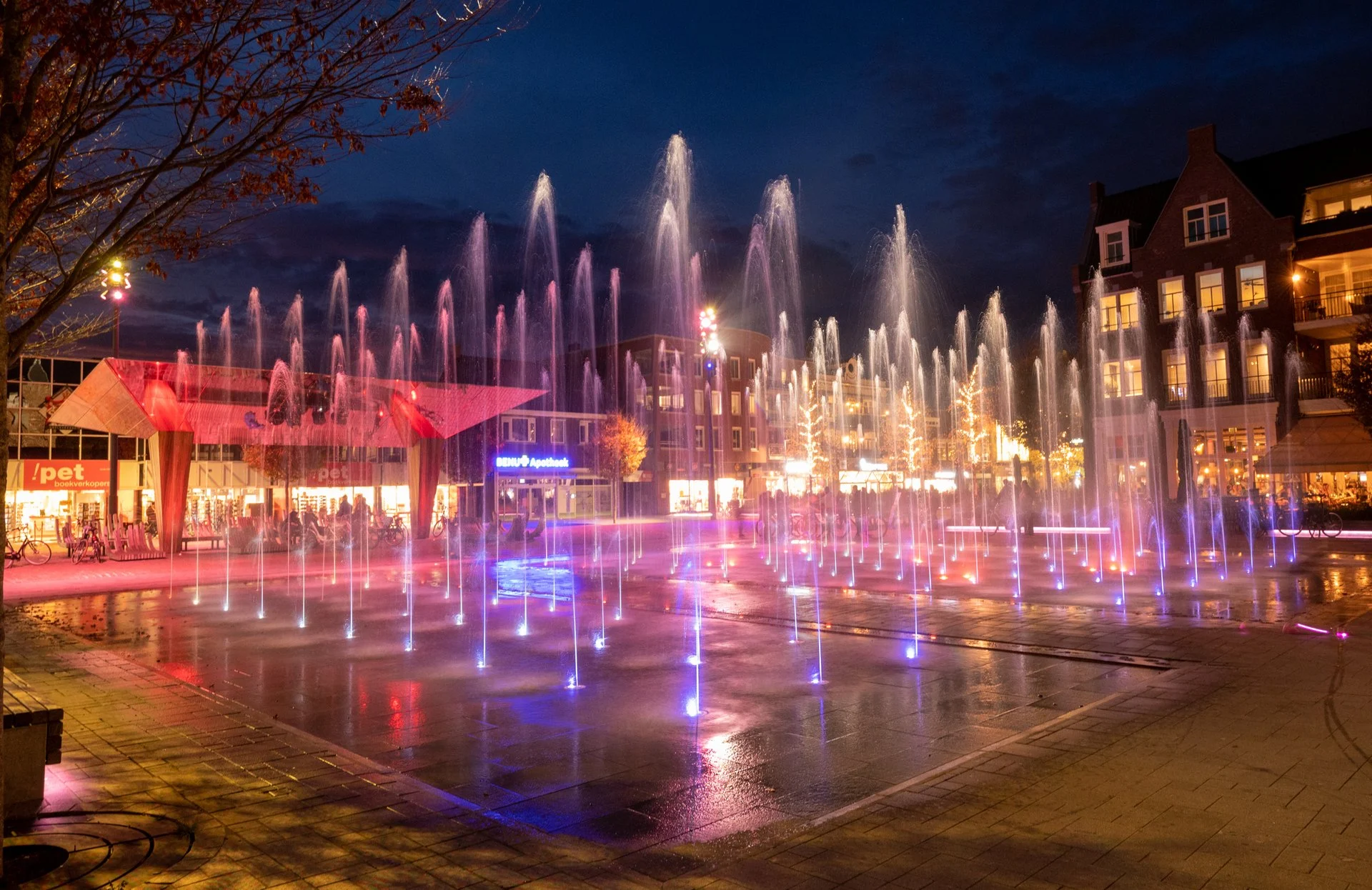 Spektakelfontein Kerkplein Hoogeveen 4 Het Kerkplein in Hoogeveen in de avond, met honderden fonteinspuiters in blauwe en paarse ledverlichting