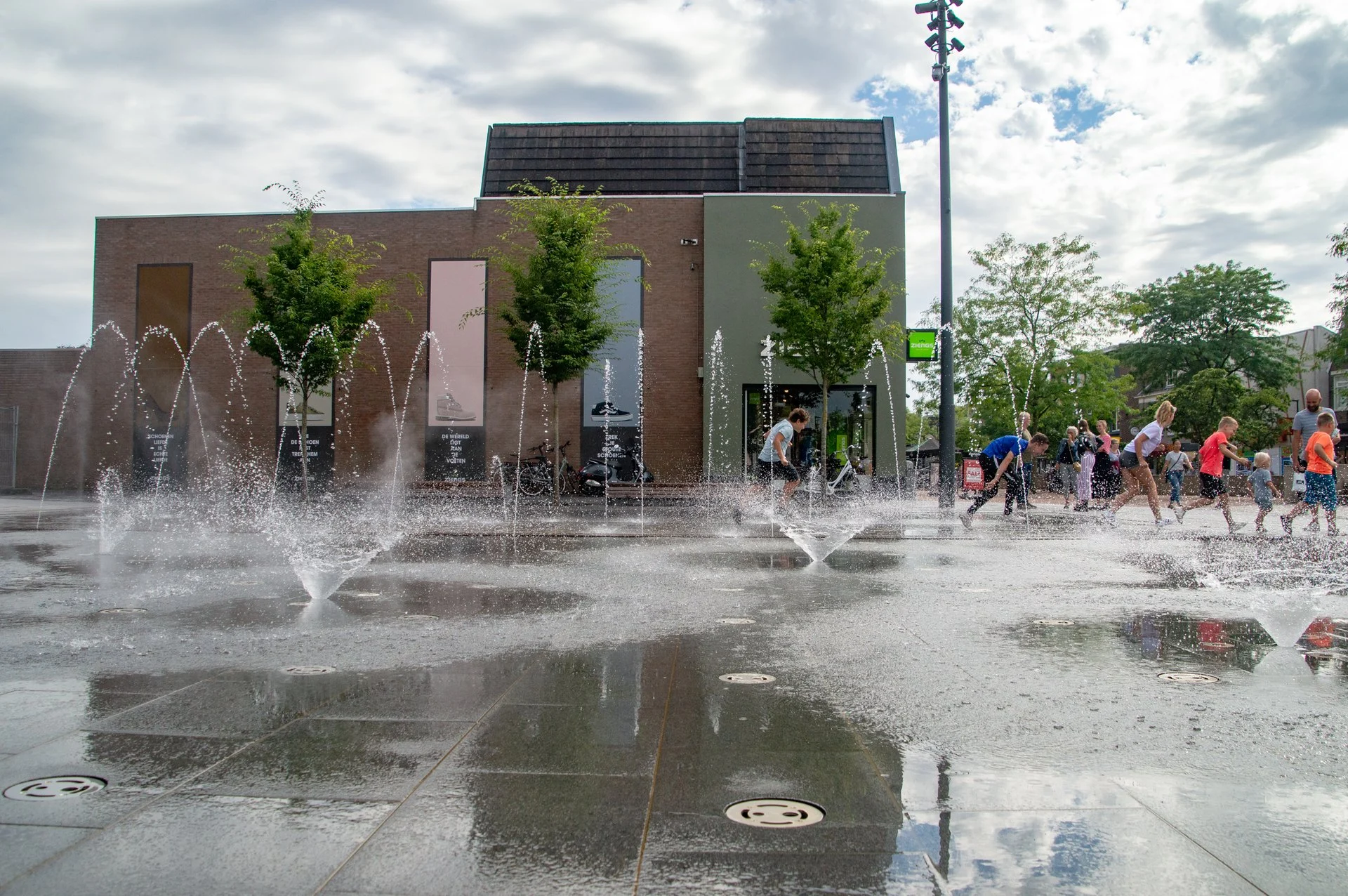 Kinderen spelen tussen de bedriegertjes en bloemfonteinen op het Kerkplein in Hoogeveen