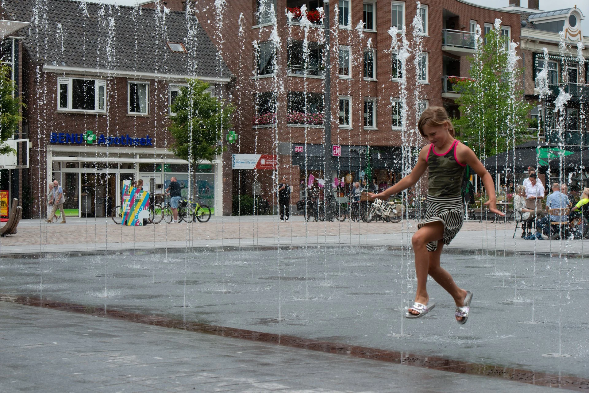 Een meisje danst door de fonteinen op het Kerkplein in Hoogeveen