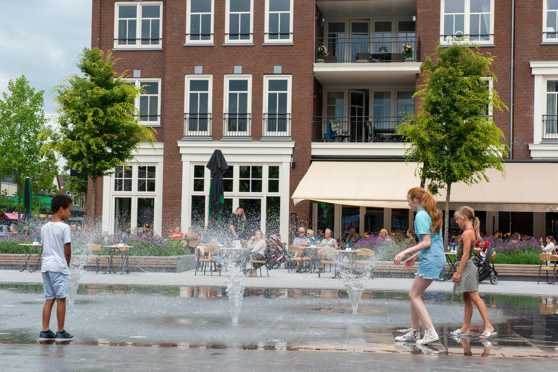 Kinderen lopen langs het spiegelvlak met bedriegertjes voor een terras op het Kerkplein in Hoogeveen