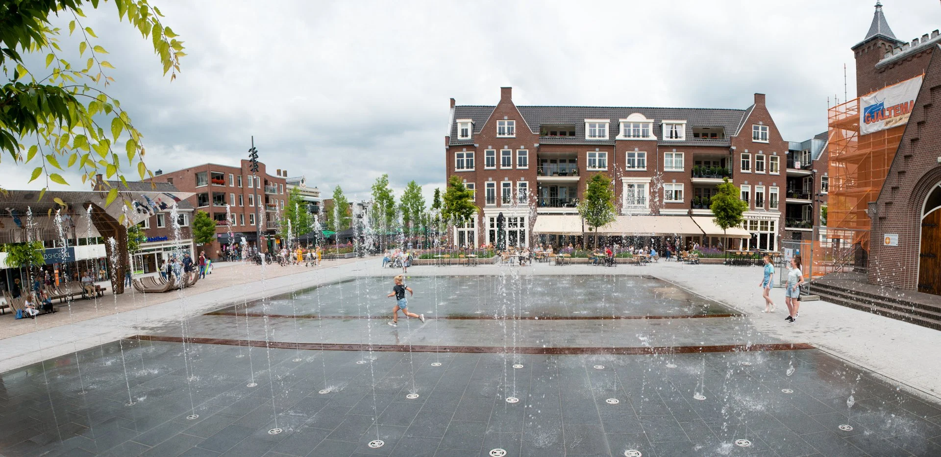 Het Kerkplein in Hoogeveen met het spiegelvlak en de fonteinen, gezien richting de kerk