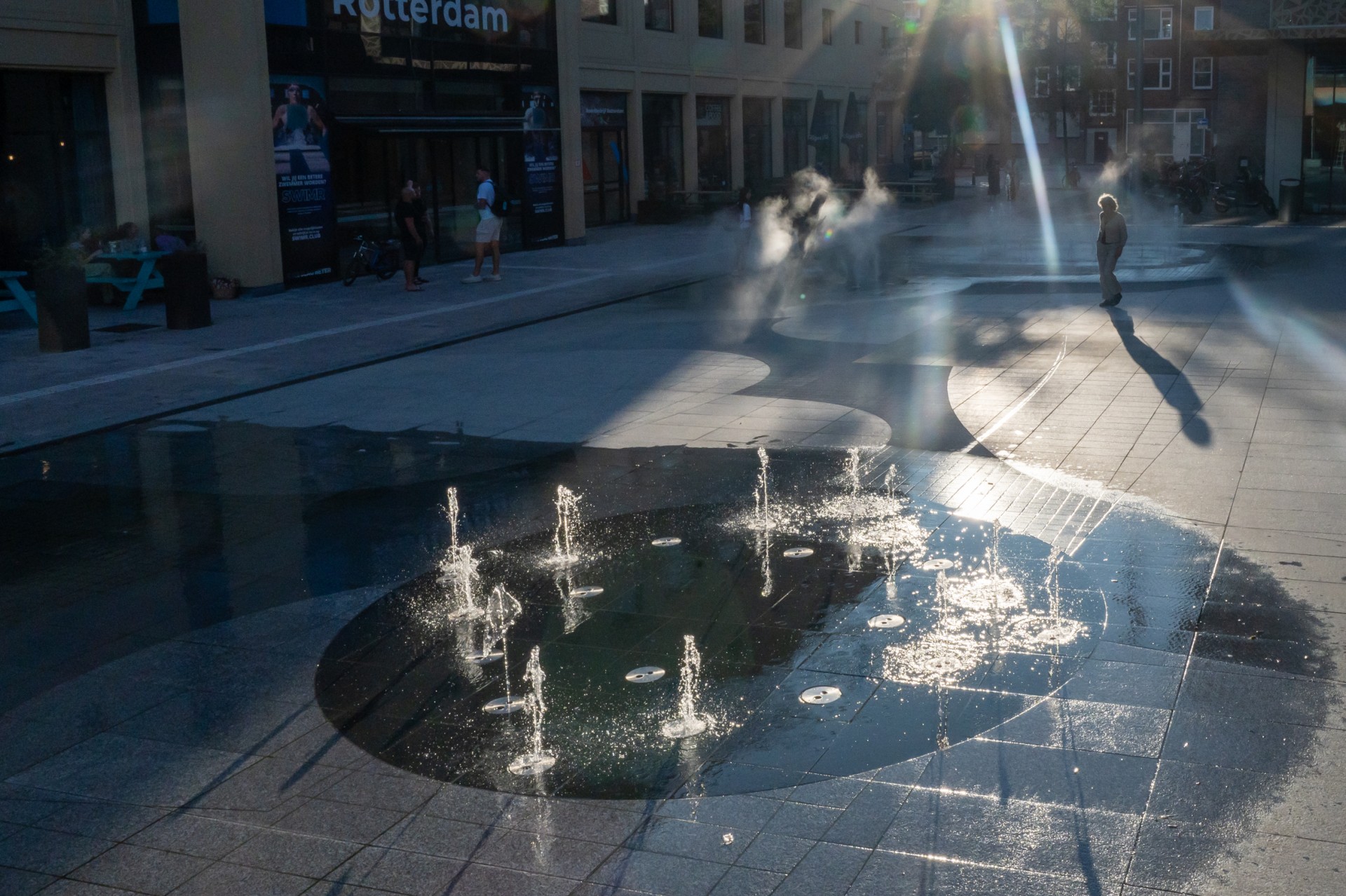 Fontein Annie MG Schmidt plein Rotterdam. Hart van Zuid Rotterdam. Natuursteen in meerdere soorten en kleuren maken een abstract pallet op de vloer. Fonteinen en nevel maken het spectakel compleet.